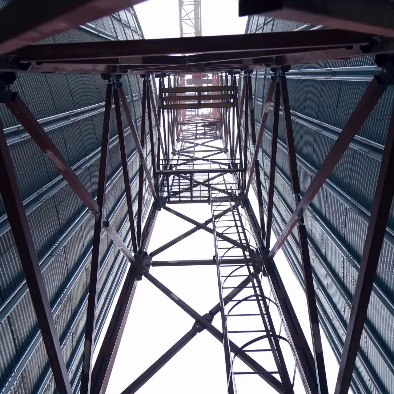 High metal support between two tanks of grain dryer. A walk between the huge tanks right under the metal support. View from below