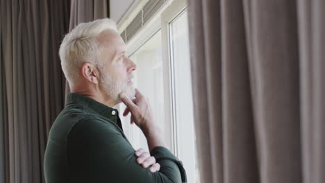 portrait of middle aged thoughtful caucasian man by window at home with copy space