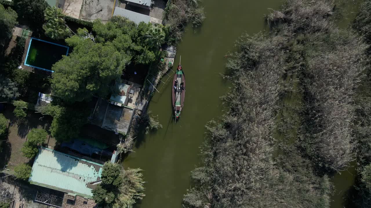 Aerial view of a boat on a canal with surrounding vegetation and buildings