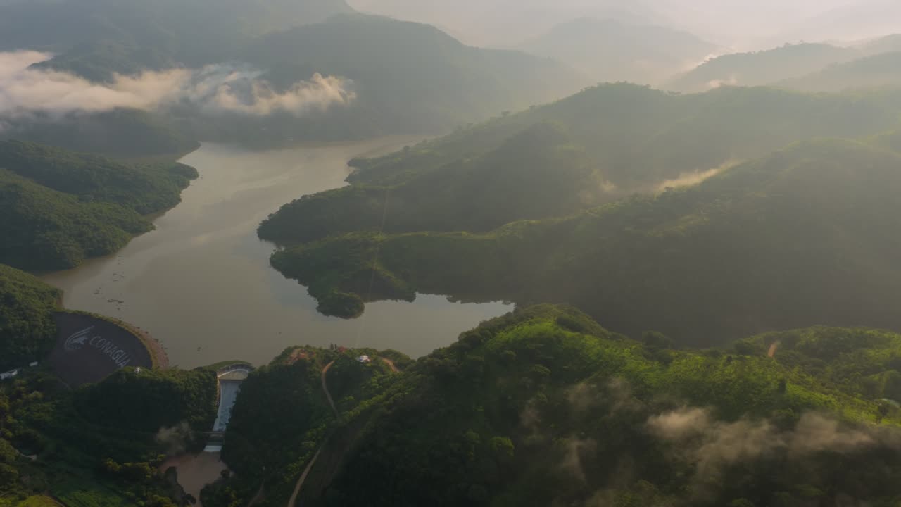 Drone video of Presa EL Carrizo, Tamazula de Gordiano, Jalisco, showcases breathtaking landscapes at sunrise. Misty hills and tranquil waters form a serene, natural panorama