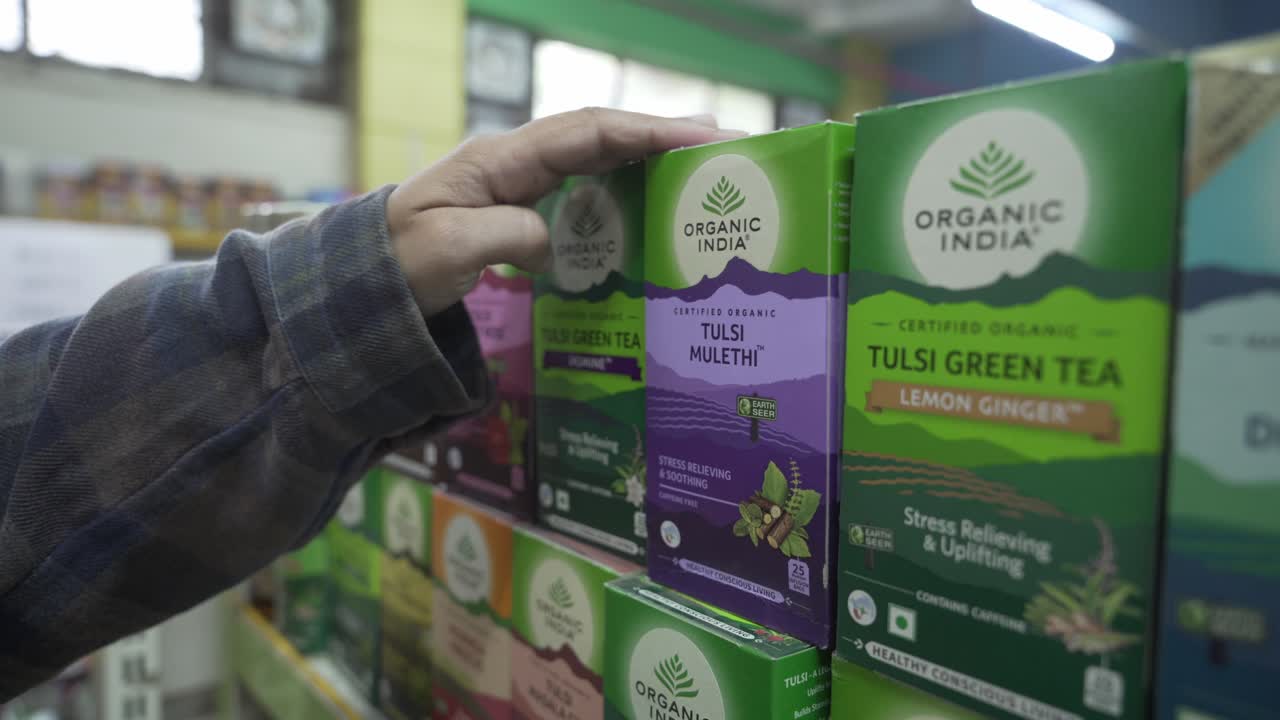 Customer picking Tulsi Green Tea made with natural herbs for good health from supermarket, Handheld shot