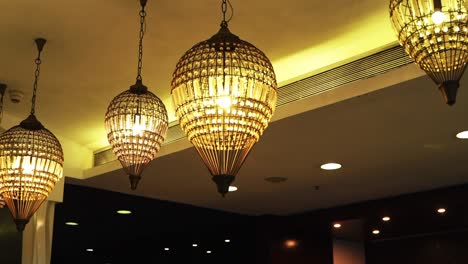 chandelier lamp hanging from the ceiling with white wall decorated in hotel banquet hall