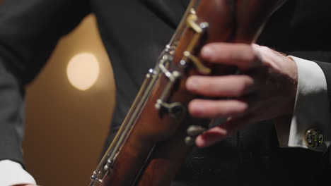 talented bassoonist is playing in symphonic orchestra man is blowing to bassoon closeup