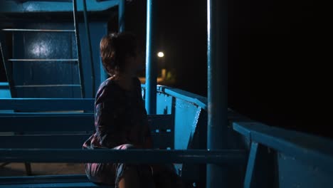 Chica-Sentada-En-Un-Barco-Durante-La-Noche---Toma-Nocturna-De-Una-Hermosa-Chica-Sentada-Sola-En-Un-Barco-De-Madera