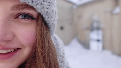 Close-up-of-cheerful-positive-young-woman-face-smiling-to-camera-while-standing-outdoors-in-winter