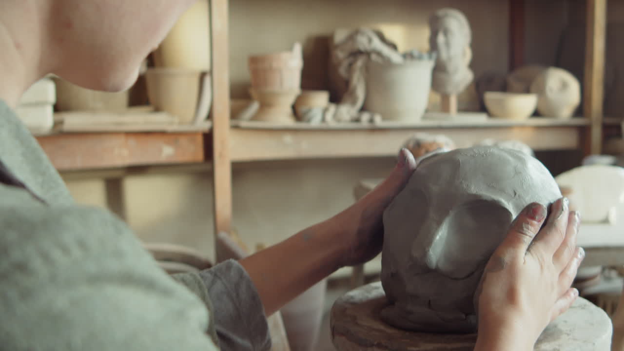 escultora modelando la cabeza de arcilla con un raspador