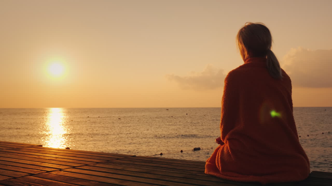 바다의 아침 - 수건으로 싸인 여성이 일출 4k 비디오를 만납니다.