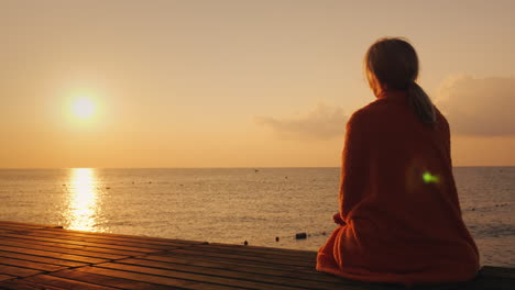 morning by the sea - a woman wrapped in a towel meets the sunrise 4k video