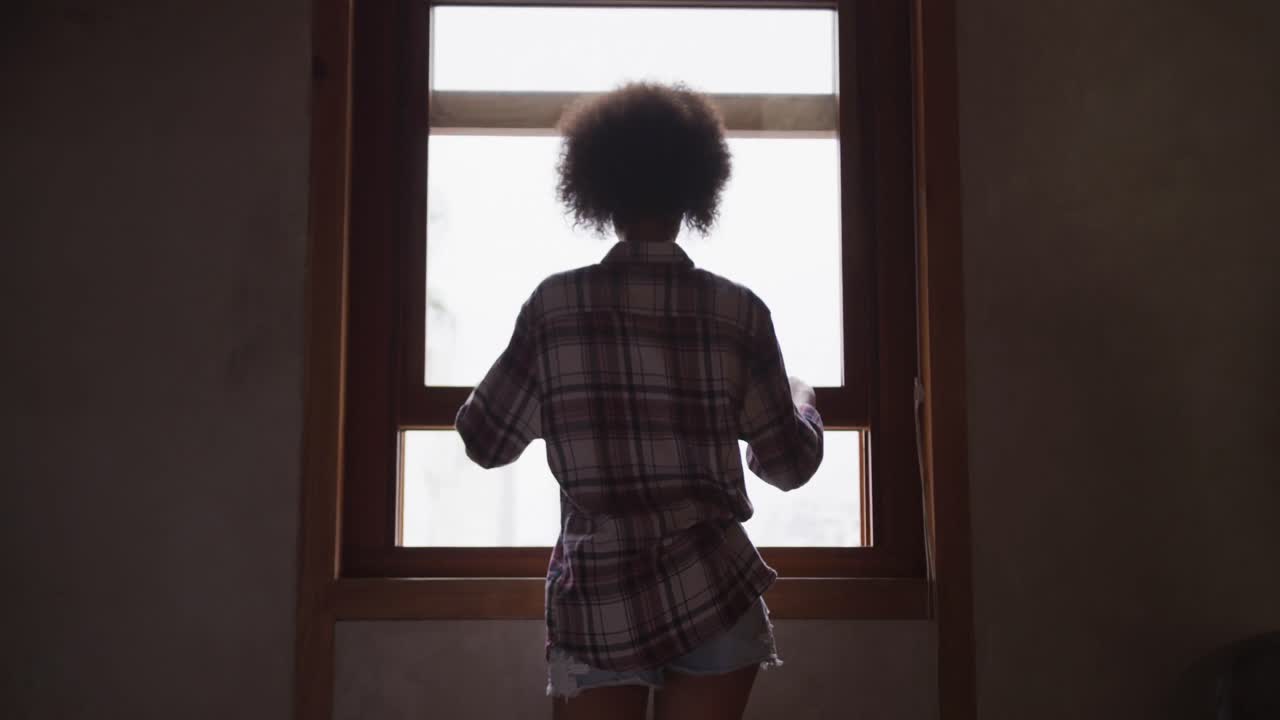 Mixed race woman opening the window at home