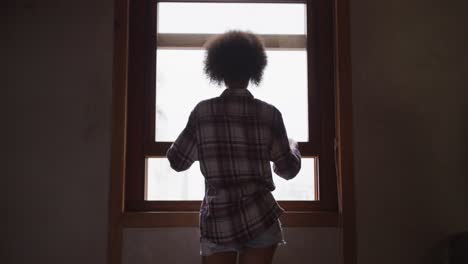 mixed race woman opening the window at home