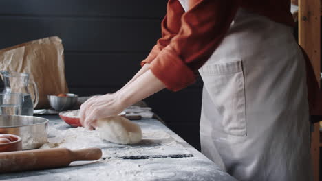 female baker kneading dough and clapping hands covered in flour