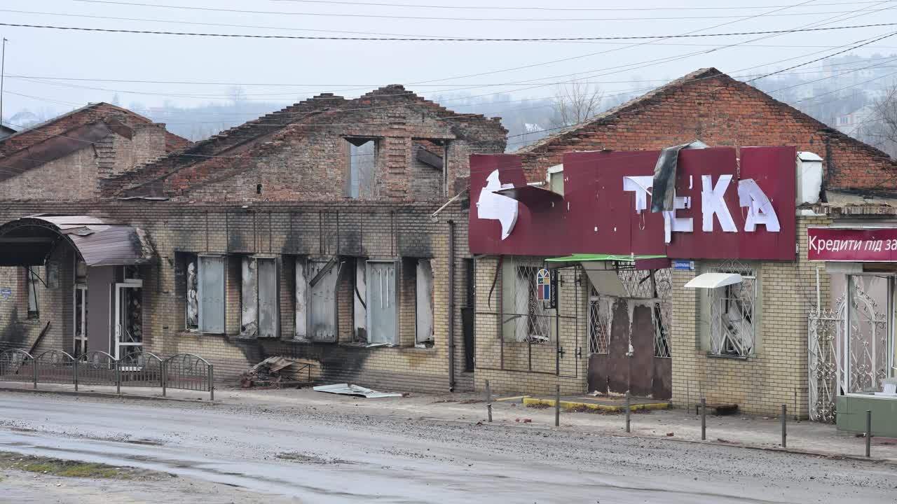 The burnt-out facade of a building stands next to a destroyed pharmacy ('Apteka') in Kupiansk, Ukraine. A stark view of local businesses shattered by Russian shelling on the frontline of the war