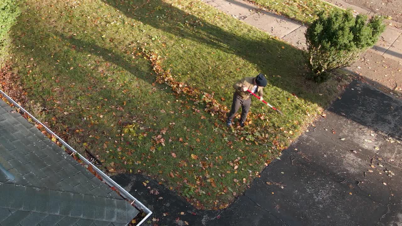 A person raking leaves into lines to clean up their yard