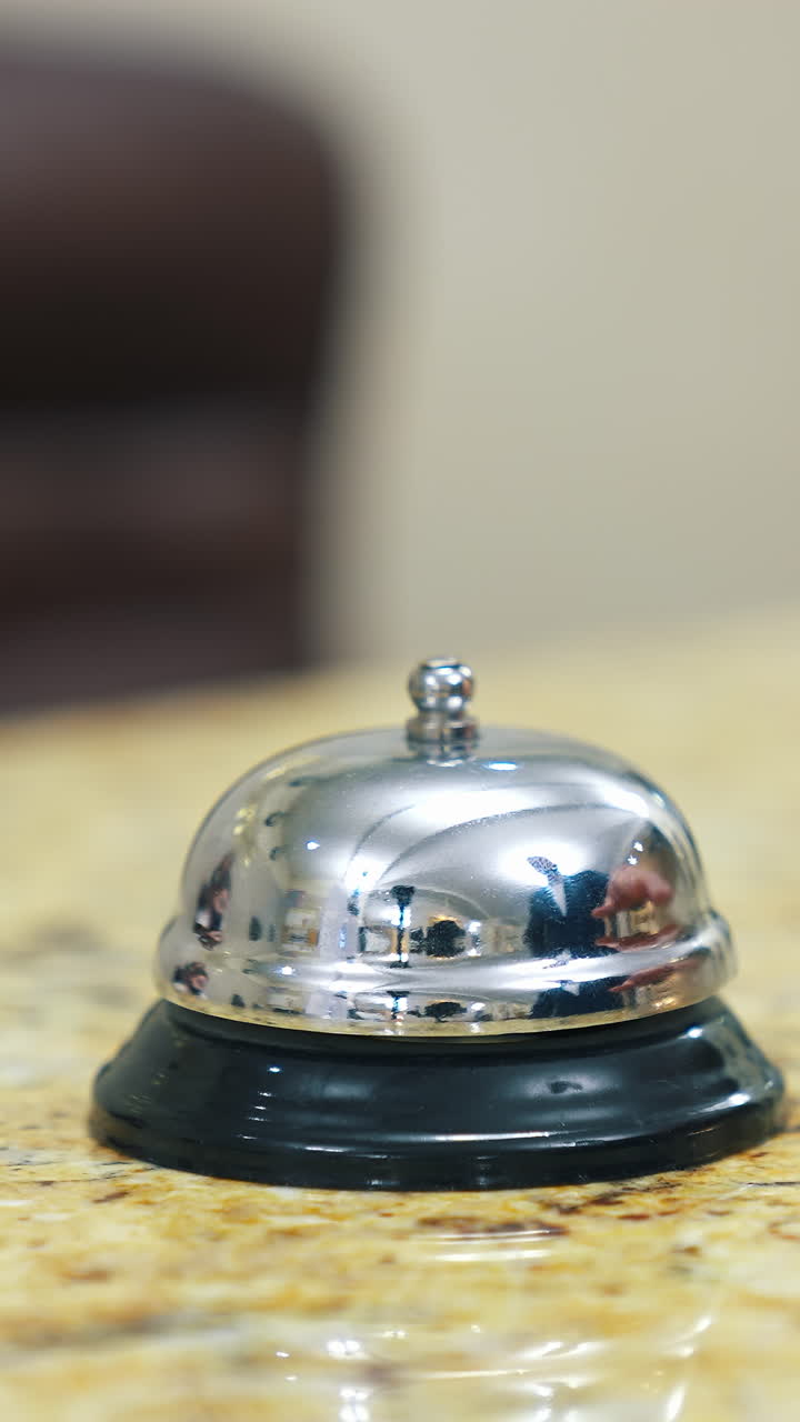 Hotel bell button on customer reception counter. The hand of the man presses the call. Bell on reception at the hotel to call the administrator. Close-up. Vertical video