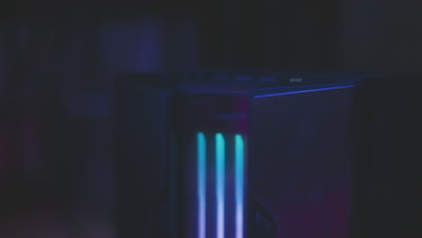 close up of sound equipment tower with glowing vertical pink lights in dark studio as user powers it on, creating ambient futuristic atmosphere with modern tech aesthetic and moody color reflections