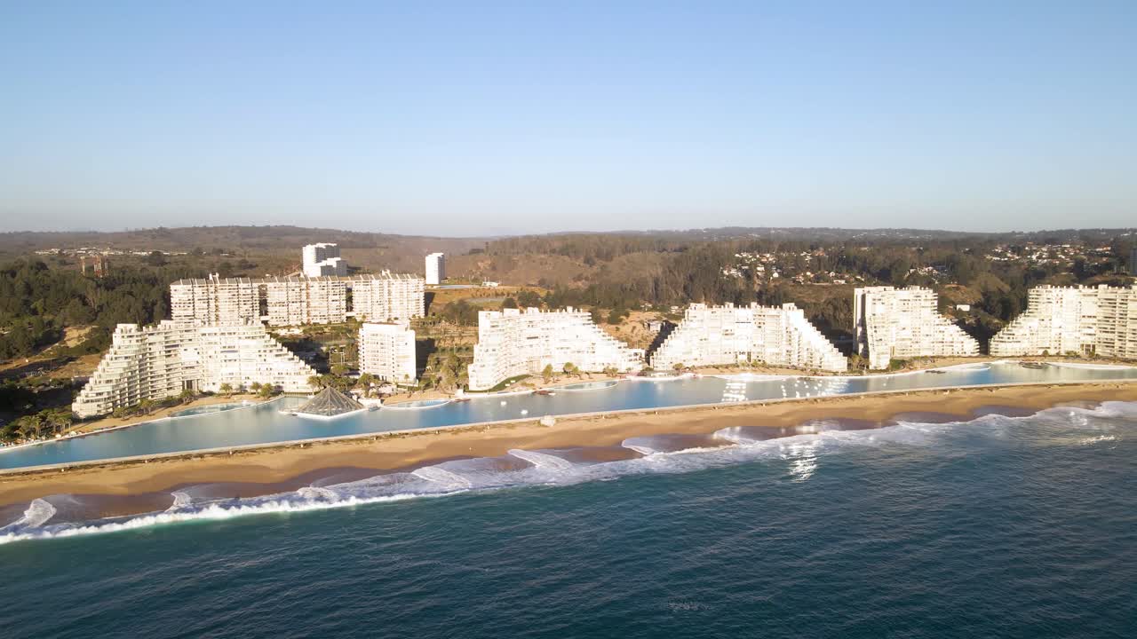 órbita aérea sobre una enorme piscina junto a edificios modernos en la playa de algarrobo, chile
