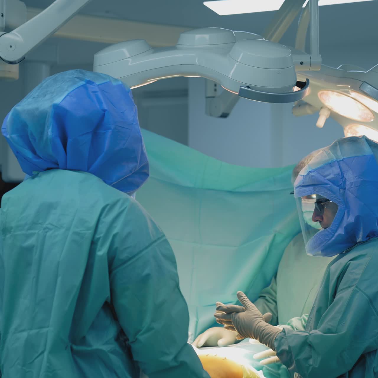 Teamwork of doctors during coronavirus pandemic outbreak in surgical room. Group of medical workers in protective costumes at work on Covid-19 crisis period