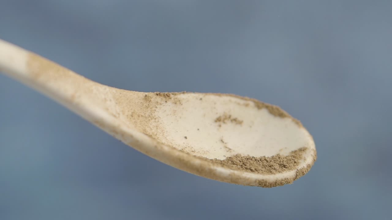 Brown Powder Pouring from a Spoon