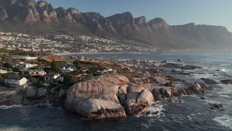 boulders at bakoven beach with twelve apostles mountains in the background in camps bay, cape town, south africa