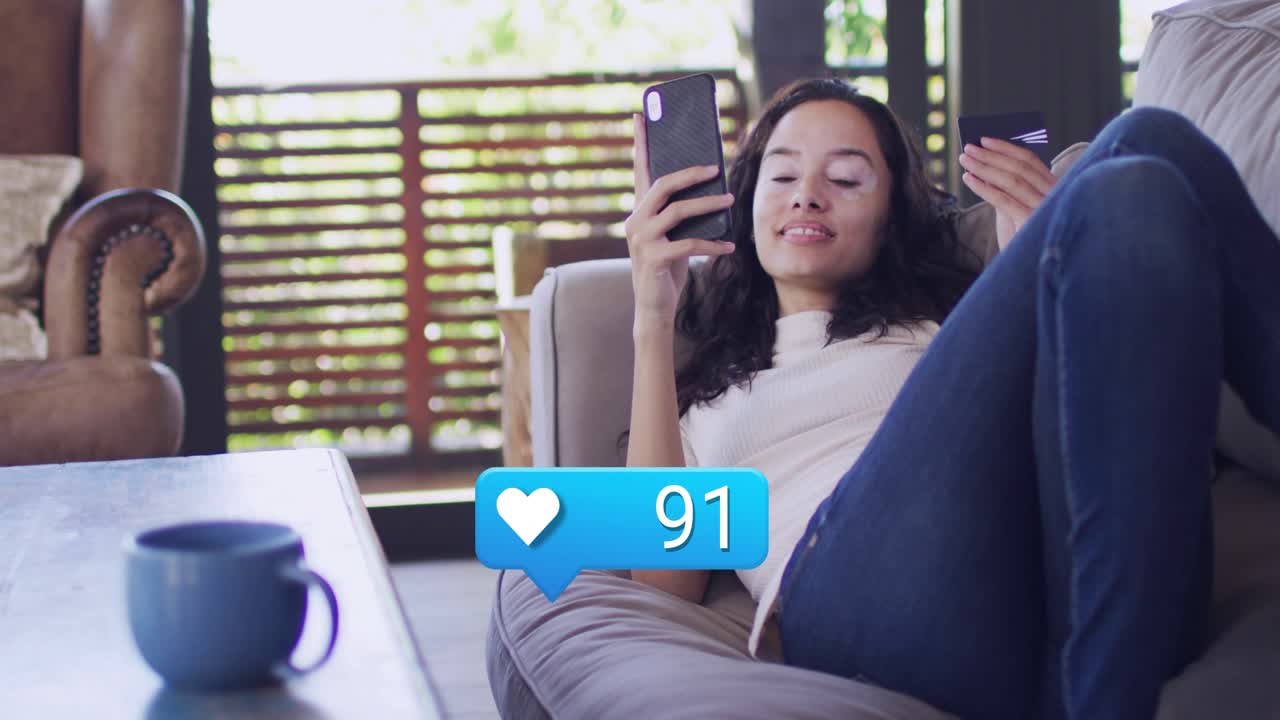 Woman reclining couch using phone watching blue social notifications hearts rising monitoring likes