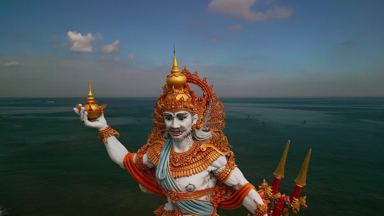 Sweeping aerial shots of Kuta Beach highlight the impressive Baruna Sea God statue, blending artistic mastery with the natural beauty of the surrounding shoreline and tropical skies