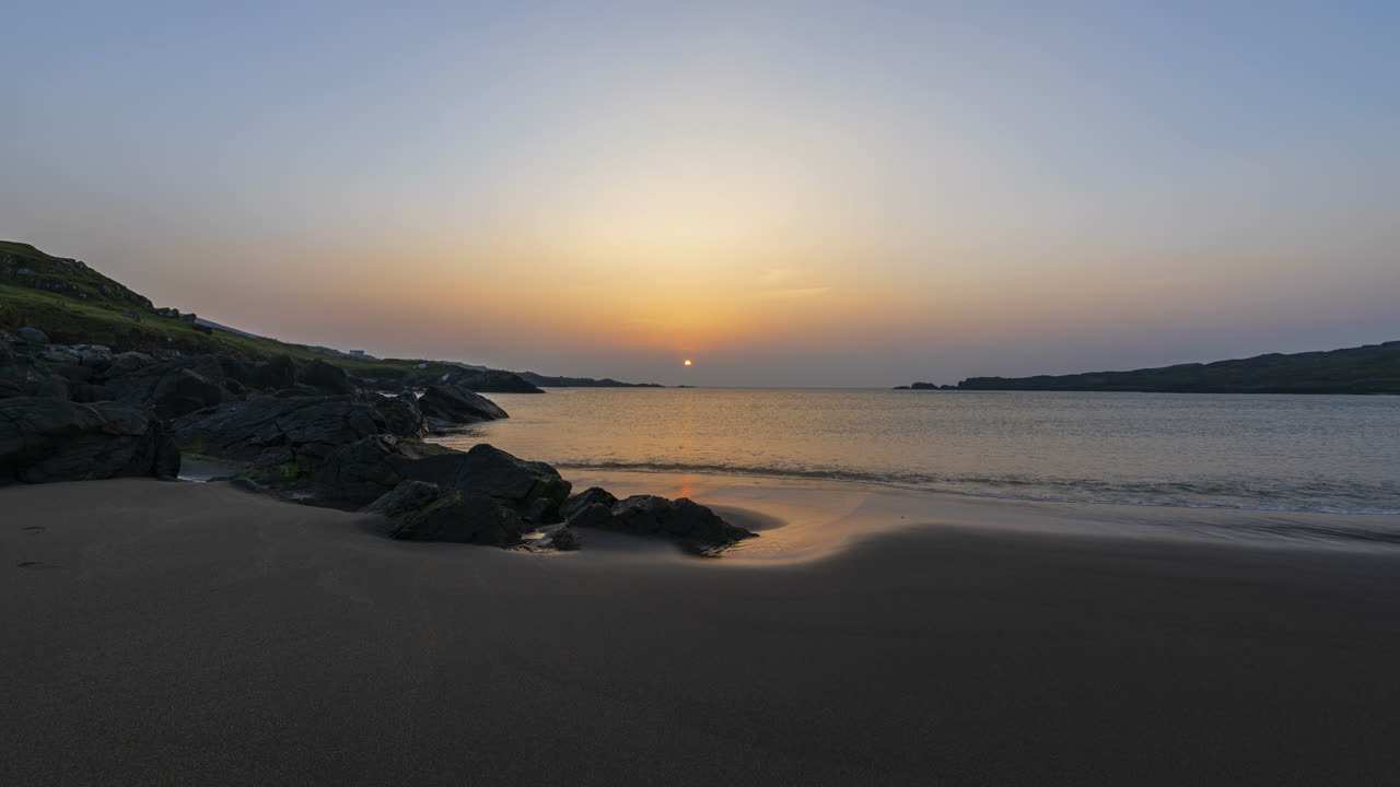lapso de tiempo de la playa de arena rocosa durante la puesta de sol con marea baja en el condado de donegal en irlanda