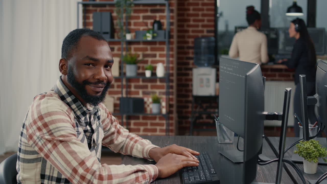 Database programer writing code and smiling while coworker walks by holding clipboard
