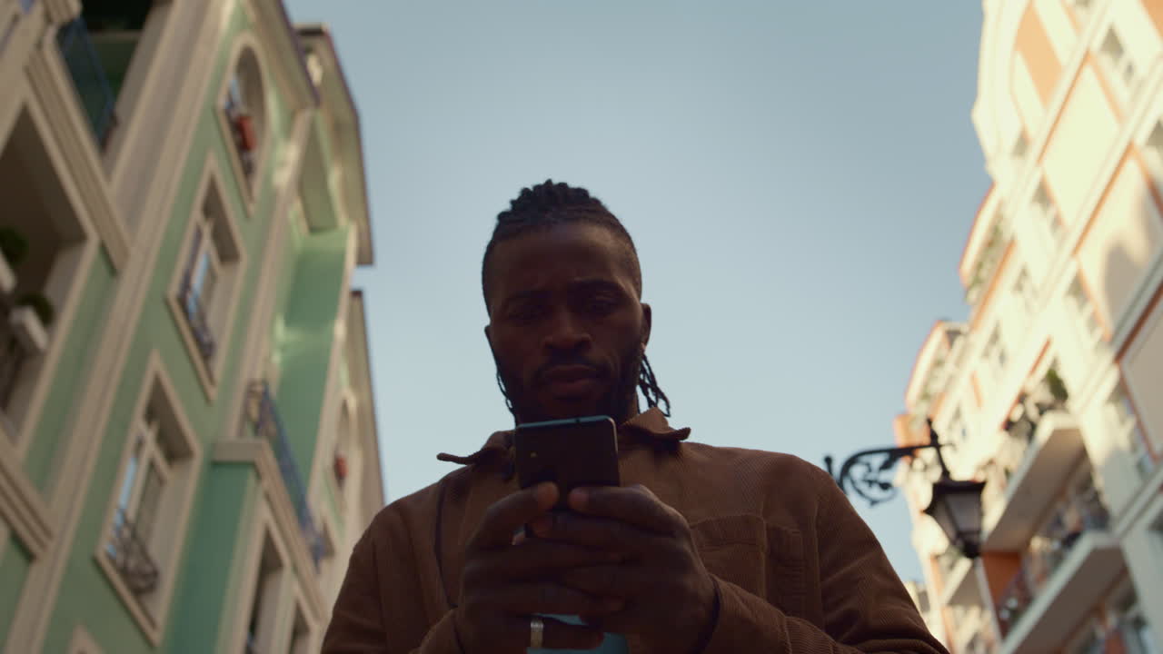 Focused man using smartphone walking street portrait. Social networking concept.