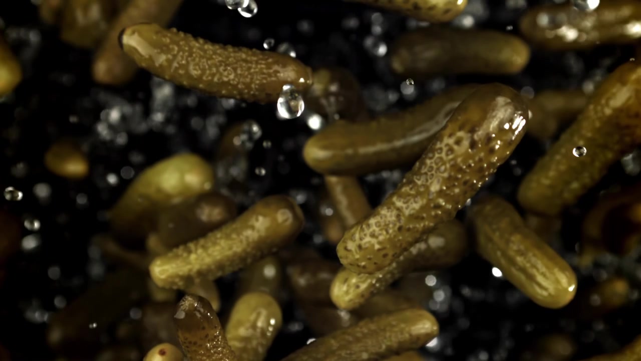 Cornichons tombant en super ralenti avec des gouttelettes d'eau