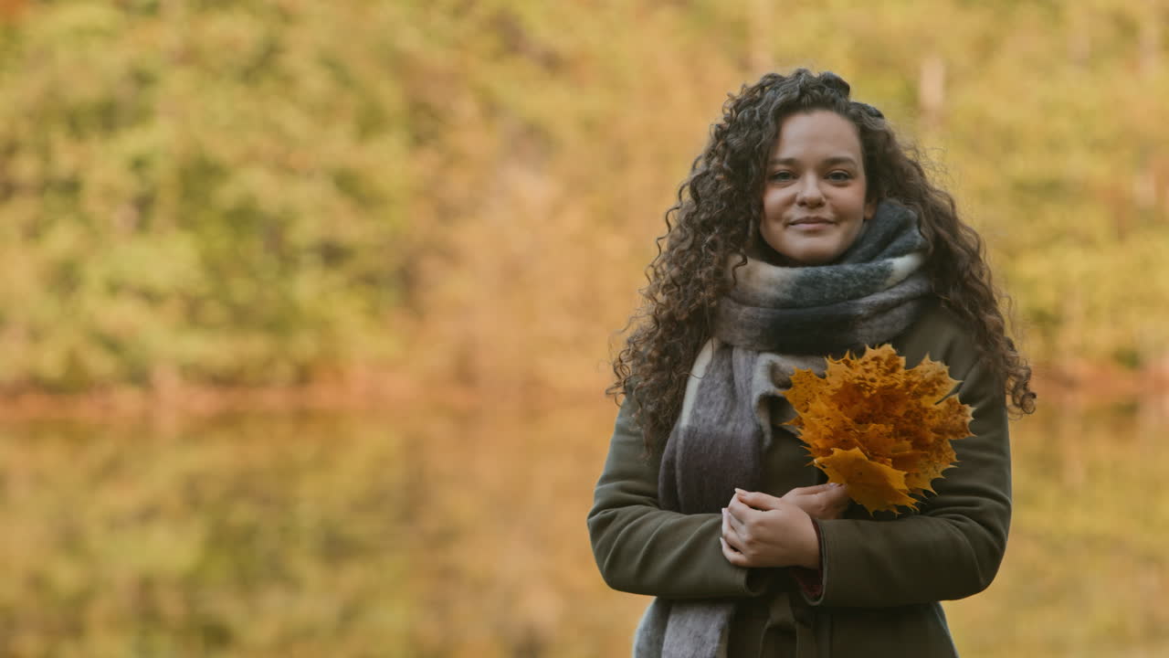 Woman with Curly Hair Holding Autumn Leaves