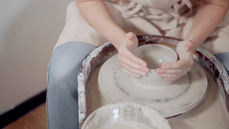 mujer haciendo un cuenco en una rueda de cerámica