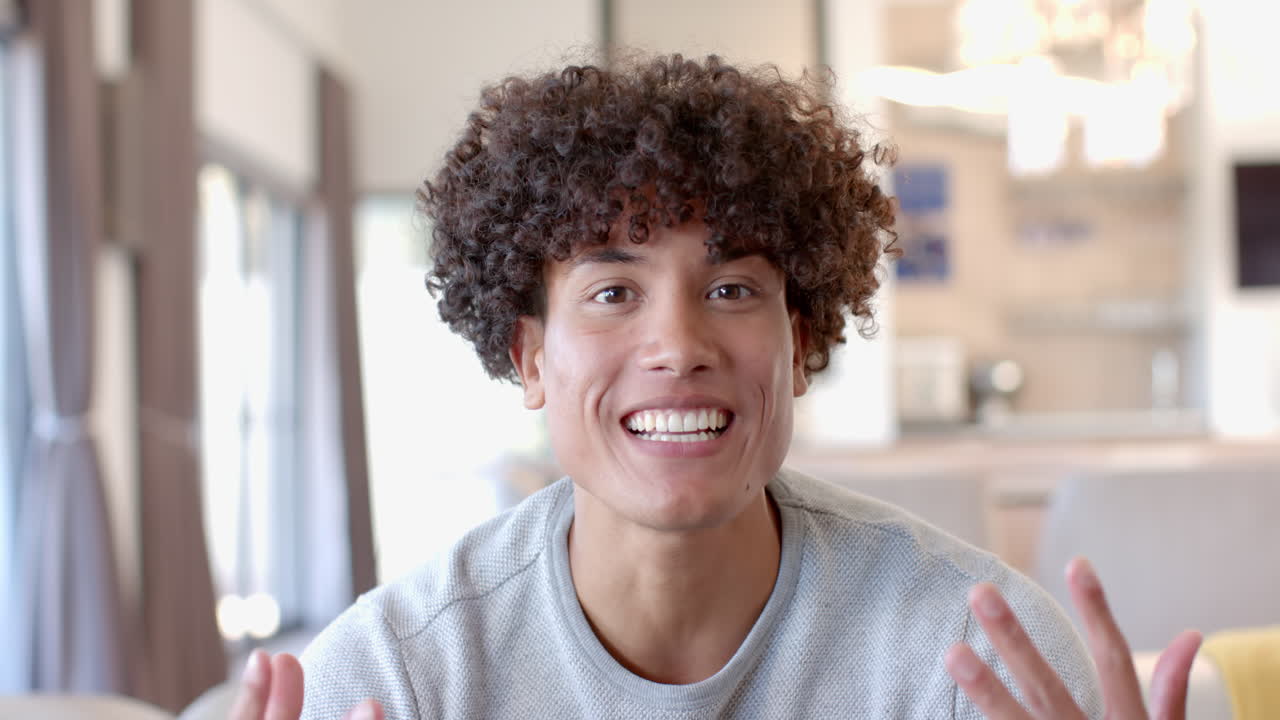 Giovane uomo sorridente che si gode il tempo con amici di diverse etnie in un accogliente soggiorno.