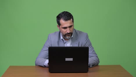 handsome persian bearded businessman thinking while using laptop