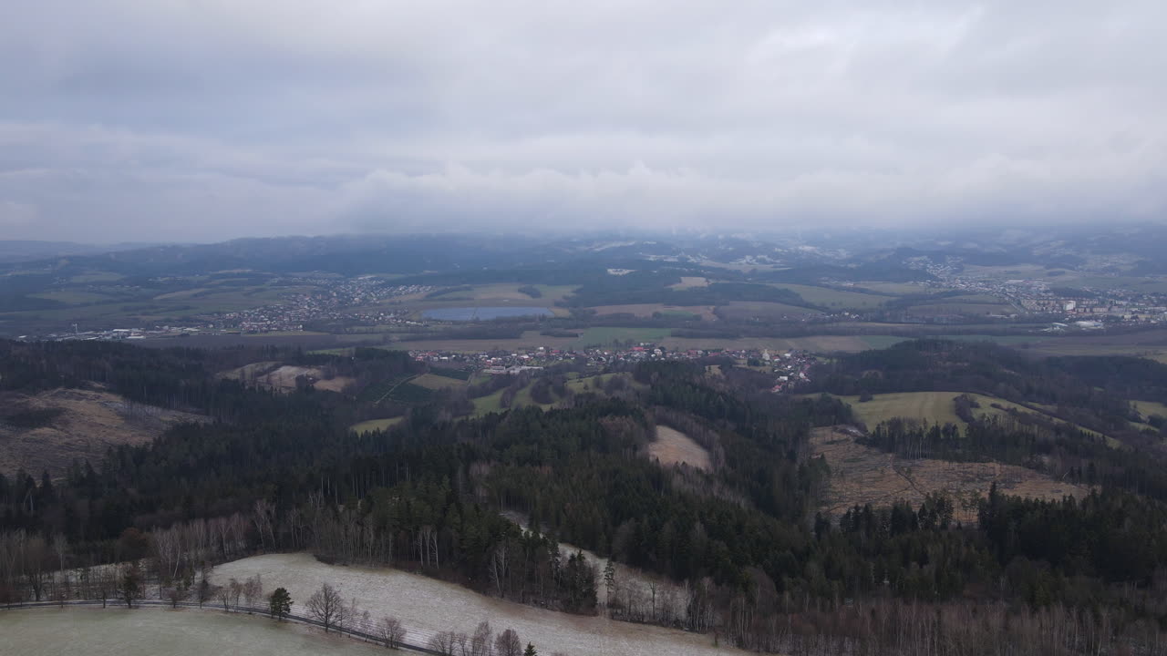 A flight over the countryside with a path leading through the trees and a view of the surrounding thing during the beginning of the snowfall