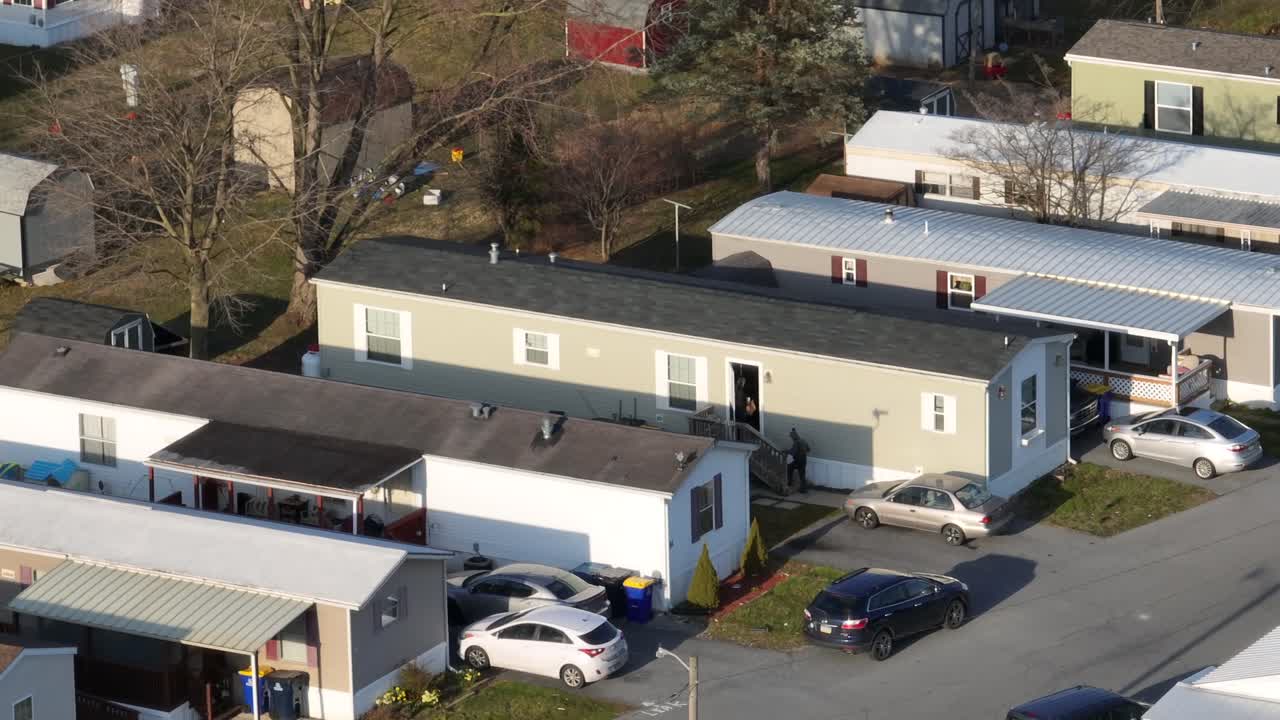 인식 할 수 없는 남자가 트레일러 파크에 있는 모바일 홈으로 들어갑니다.