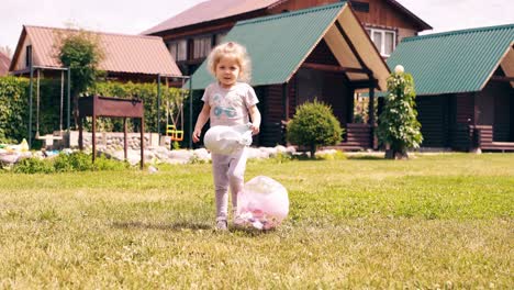 tracking little cute baby runs around lawn and kicks ball