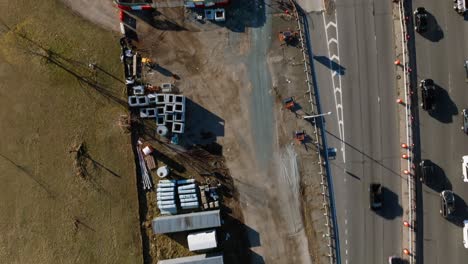 a top down view of a construction site with equipment and vehicles parked by the belt parkway and a park in brooklyn, ny on a sunny day