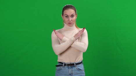 mujer caucásica atractiva y seria sacudiendo la cabeza no y cruzando las manos mirando a la cámara. retrato de una hermosa dama insatisfecha posando en el fondo de la pantalla verde chromakey. negación y rechazo