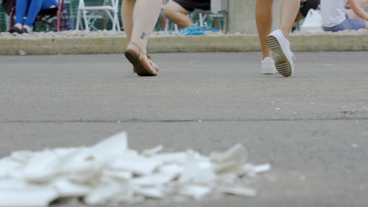 People walking on a path, with trash on the ground
