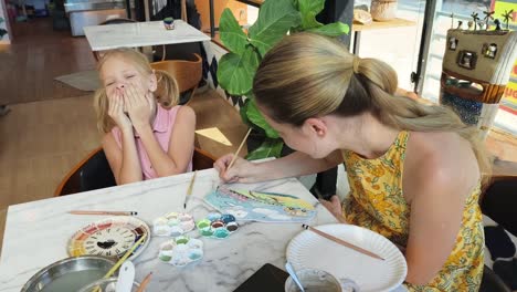 mother and daughter painting ceramics in a cafe