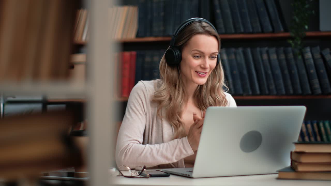 mujer con auriculares hablando en línea llamada de video usar portátil e aprendizaje a distancia escritorio de biblioteca