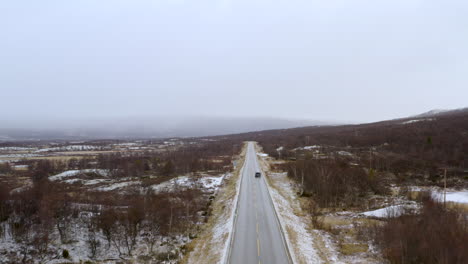 car on the road in winter forest with snow covered landscape - snowy outdoor scene - traveling concept background - aerial drone shot