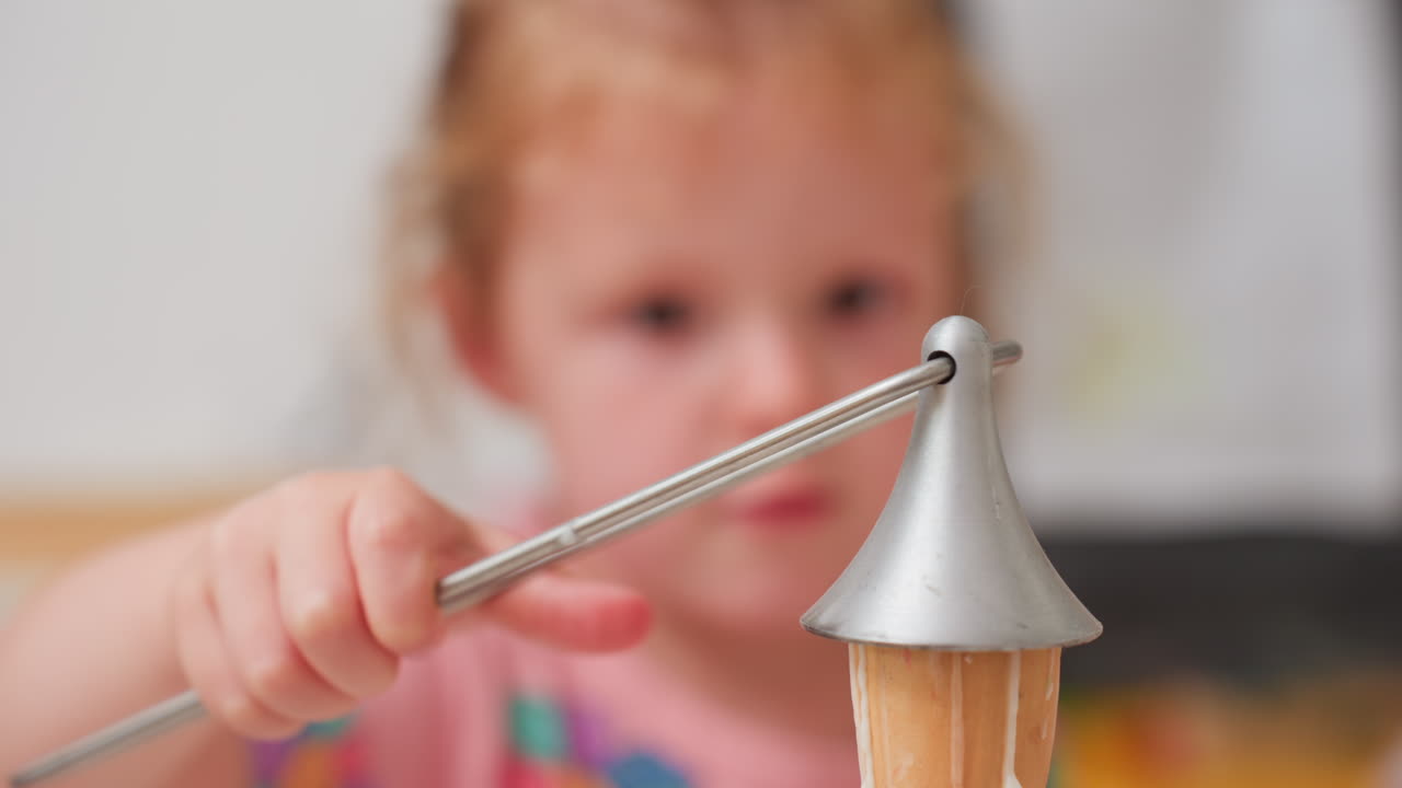 Close up of adult guiding child using snuffer to extinguish candle flame, warm wax melting as gentle hands show careful motion teaching safety awareness and control
