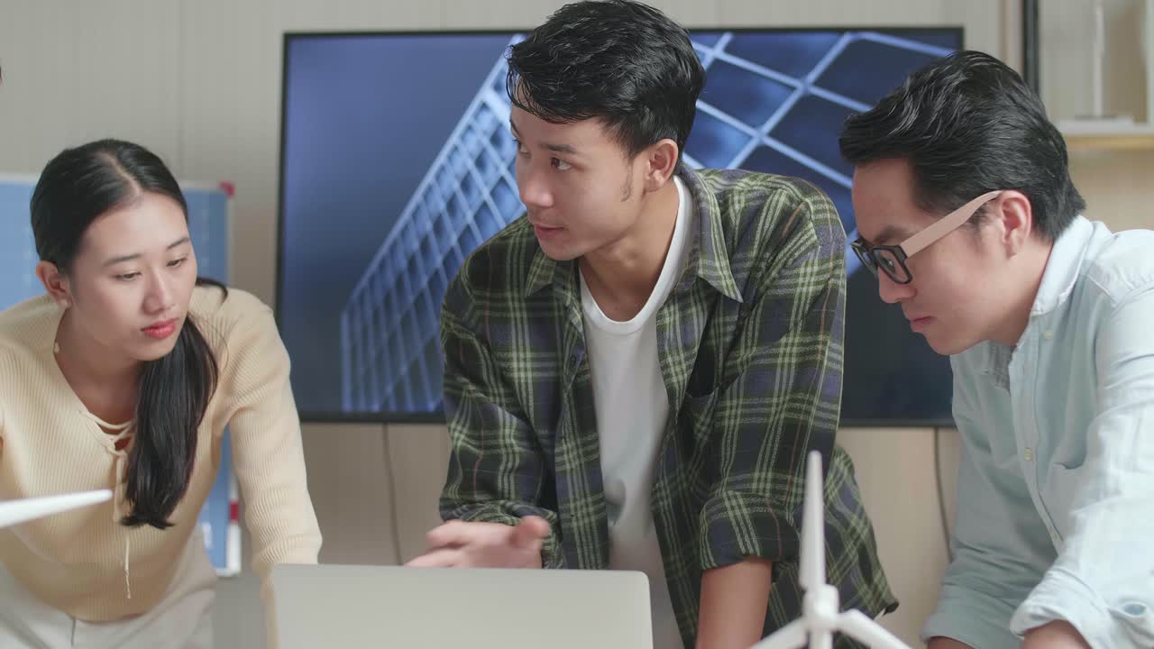 태양 전지 패널 집 모델과 함께 아시아 엔지니어 그룹의 클로즈업은 사무실에서 노트북 작업에 대해 논의합니다.
