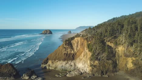 Atemberaubende-Luftaufnahmen-Der-Westküstenlandschaft-In-Oregon---Lion-Rock-In-Der-Nähe-Von-Cannon-Beach---Großer-Leerer-Strand-Mit-Wunderschönem-Grünen-Wald-Und-Riesigen-Bäumen