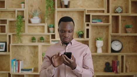 Retrato-De-Un-Exitoso-Hombre-De-Negocios-Afroamericano-Sonriendo-Alegremente-Usando-Mensajes-De-Navegación-En-Teléfonos-Inteligentes