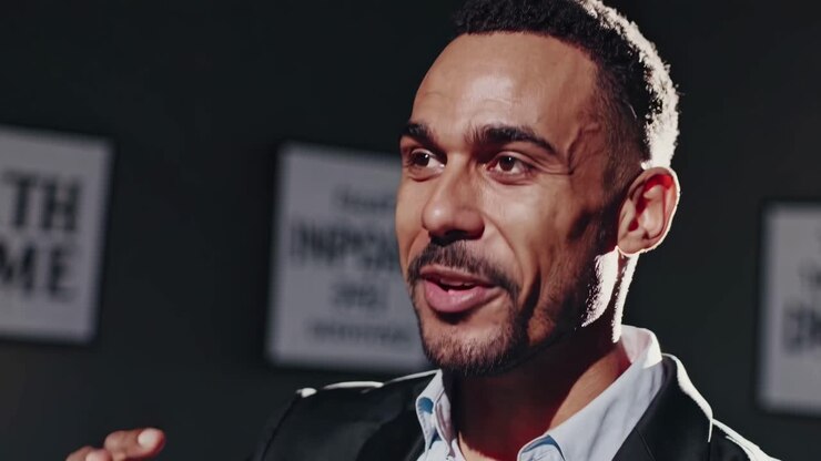 Close-up video of a smiling man in a suit, shot from a low angle