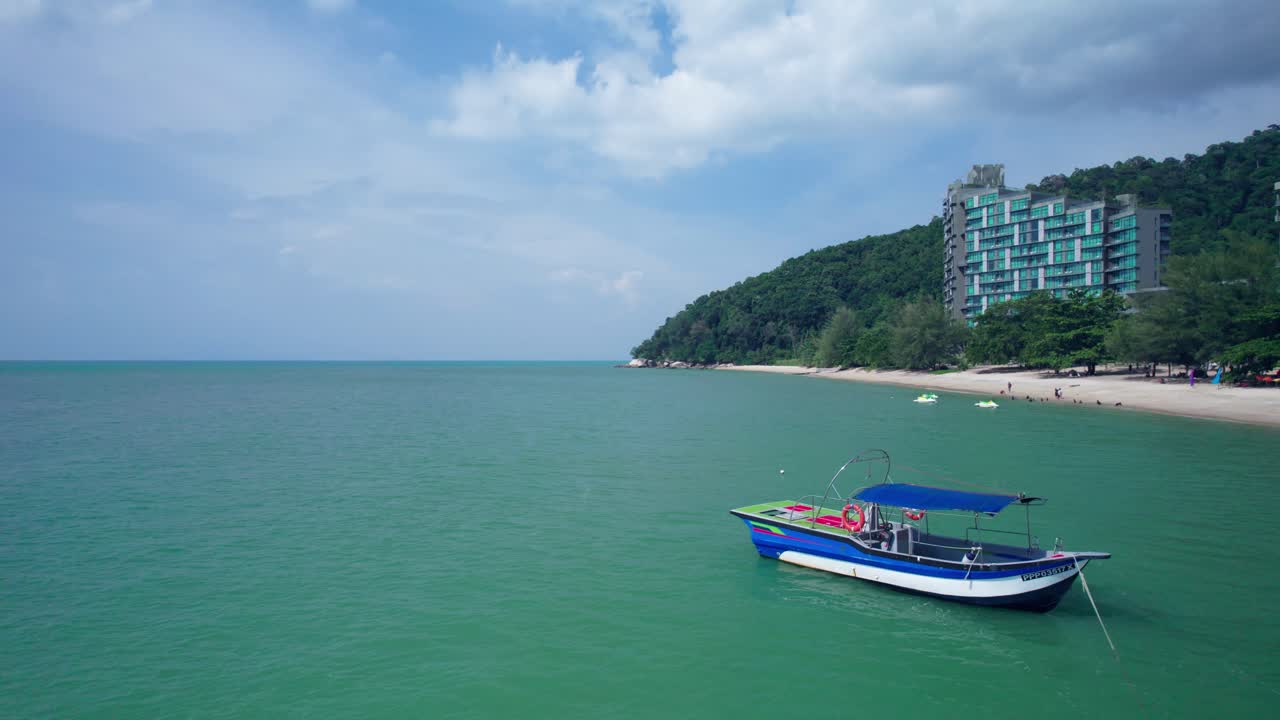 Aerial footage showing a small boat resting offshore with coastal structures in the background