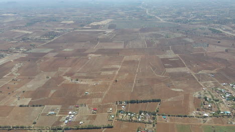 Aerial-pan-over-small-settlements-and-revealing-a-distant-town-in-rural-Kenya