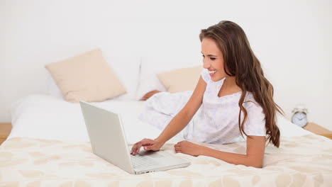 Mujer-Joven-Usando-Su-Computadora-Portátil-Acostada-En-Su-Cama.